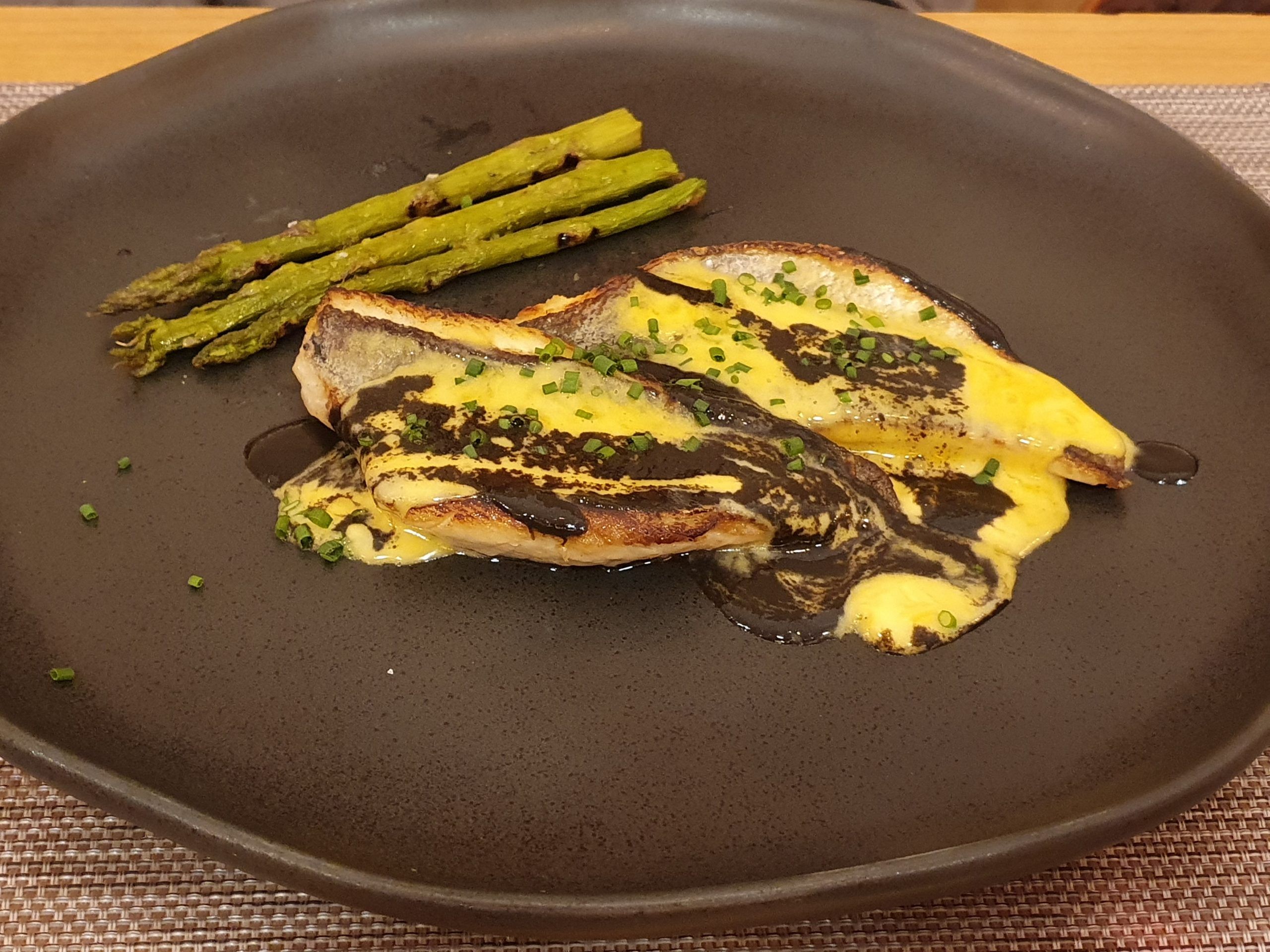 Lomos de dorada a la plancha con holandesa de lima, salsa tinta y trigueros a la brasa