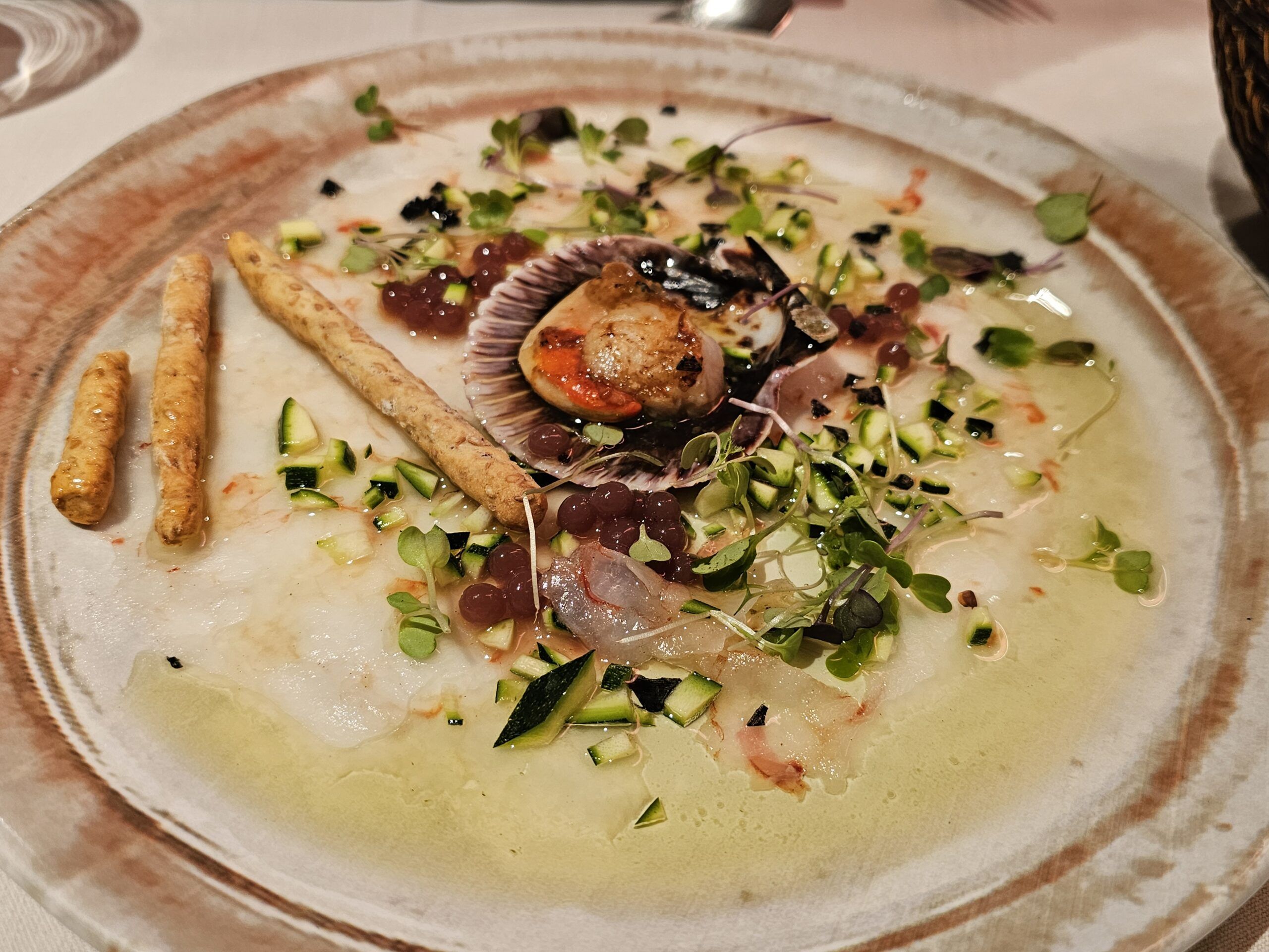 Carpaccio de gambones con zamburiña a la sal y esferificación de granada