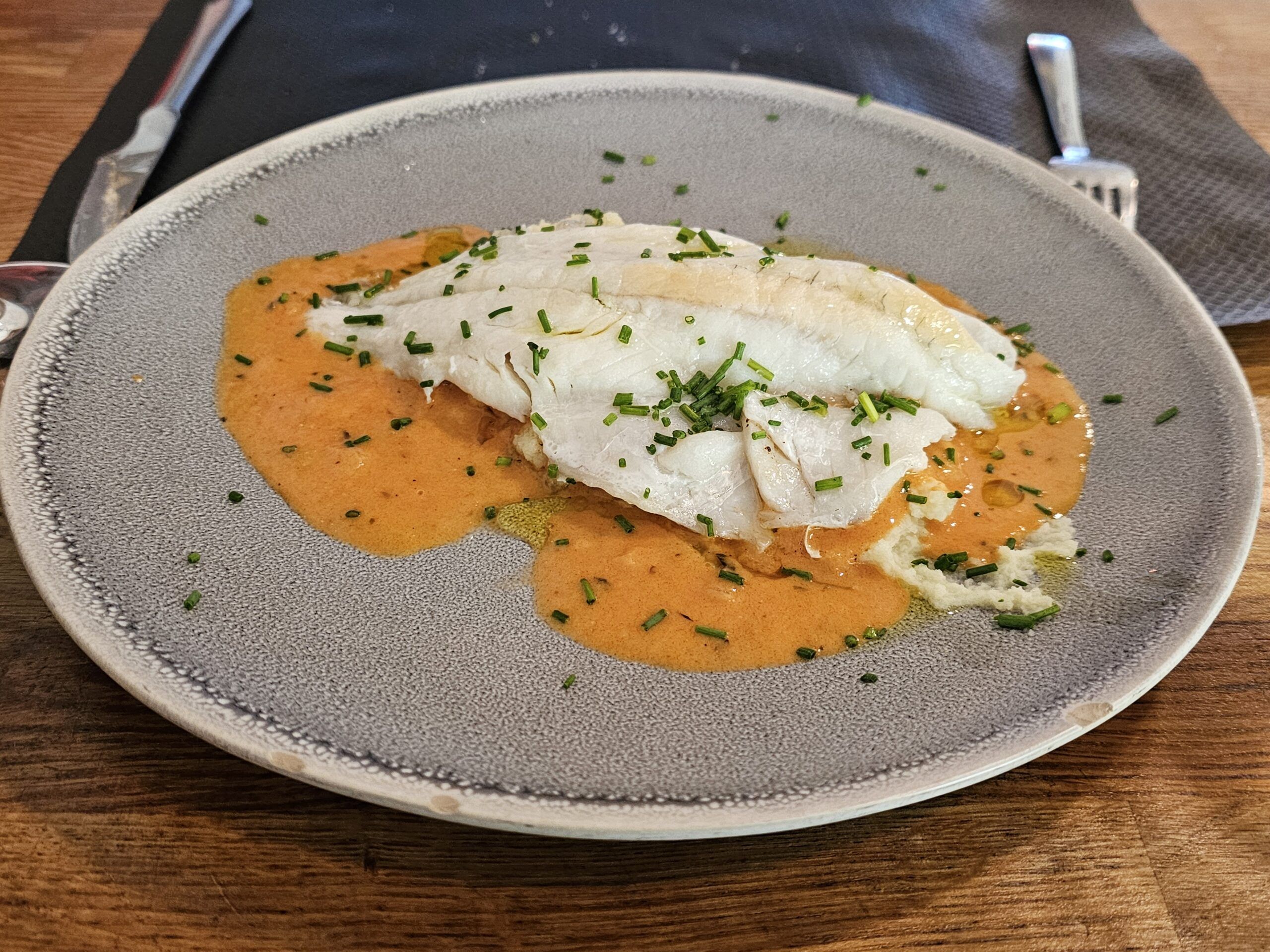 Lubina al papillote con salsa de mariscos y puré de patatas